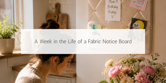 Handmade ivory fabric notice board helping organise everyday life, with handwritten reminders in a bright kitchen while a woman writes a birthday card nearby.